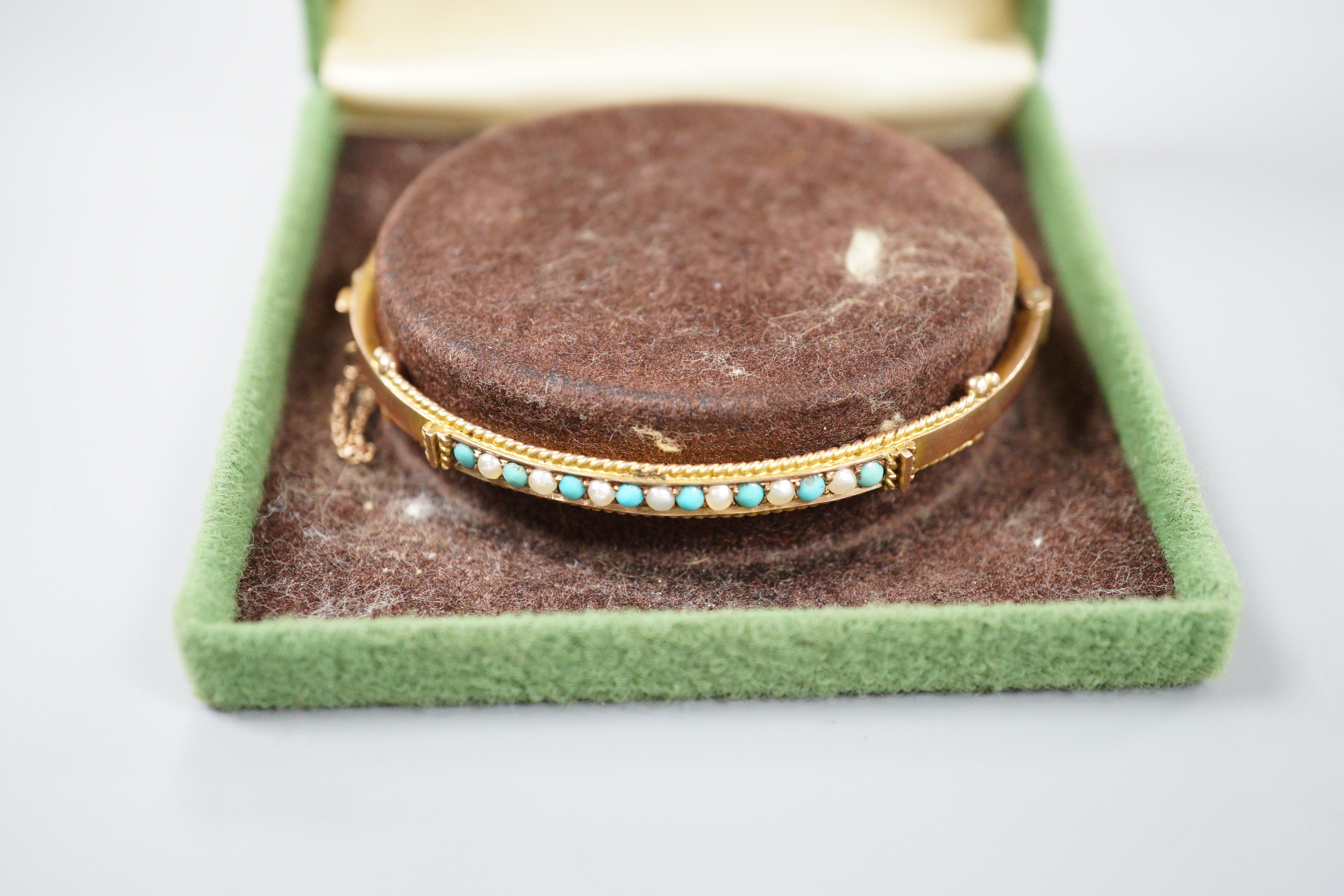 A late Victorian 9ct gold, seed pearl and turquoise set hinged bangle, 58mm, gross weight 6.7 grams.